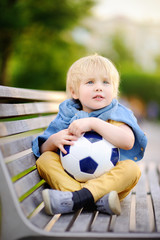 Little boy resting after playing a soccer/football game on summer day