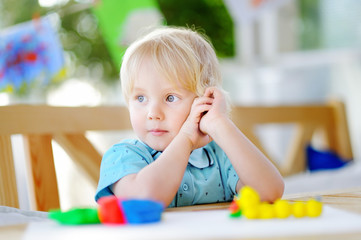 Creative boy playing with colorful modeling clay at kindergarten