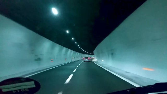 Cars driving along speed highway in brightly lit tunnel, extreme pursuit on road