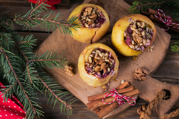 Baked apples stuffed with berries, walnuts and honey on a wooden cutting board.