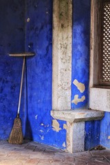 Abandoned broom and Colorful texture in an old blue painted wall