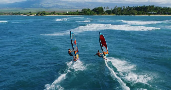 Cinematic aerial view of windsurfers sailing across the ocean