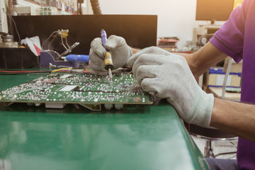 The man using soldering iron on circuit of PCB board on table ESD mat.