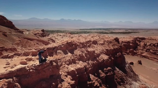 Aerial shot of male hiker lifting his backpack to return to the path at Atacama desert. 4k