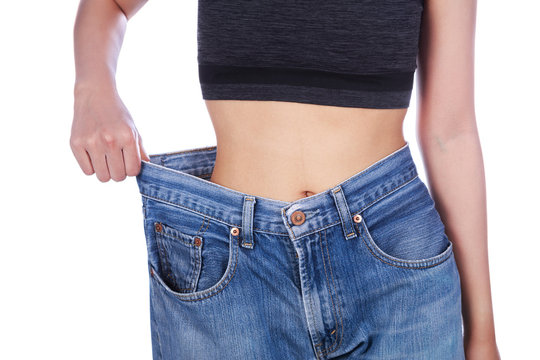 close up of woman show her weight loss and wearing her old jeans isolated on white background