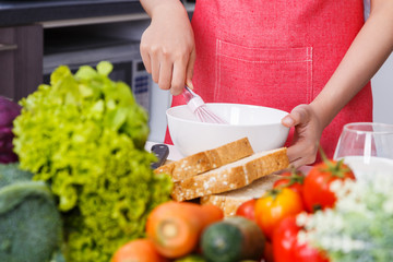 close up of hand cooking and whisking eggs in a bowl in kitchen room