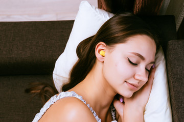 cute young girl sleeping, in the ears yellow earplugs against street noise