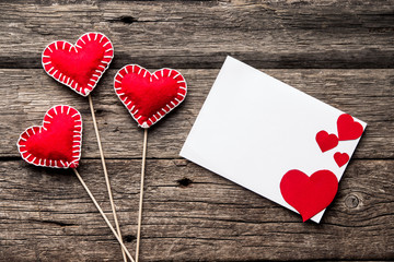 Valentines day background. Red hearts, ribbon and message card on wood background.