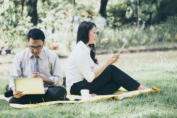 Obraz premium Happy Asian business people are dicussing, working and relaxing while sitting in the park.