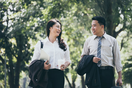 Happy Asian Business Man And Woman Walking And Talking In The Public Park After Finish Work.