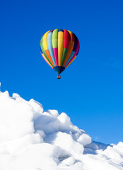 Colorful hot air balloon flying over snowy field in winter