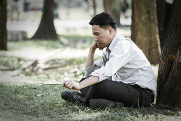 Naklejka na ściany i meble Asian business man failing and serious under tree in the park