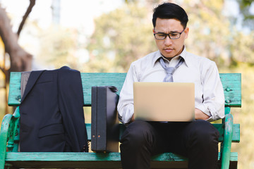 Asian business man working failing serious on laptop in the park