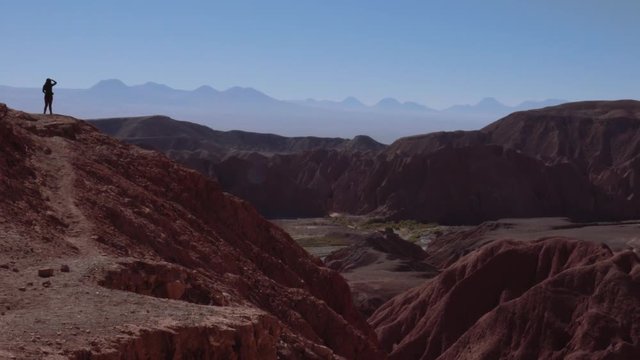 Aerial shot of female trekker standing at the cliff contemplating the horizon of the Atacama desert. 4k