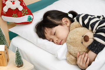 Child girl sleeping on the wooden bed with teddy bear in her bedroom, Happy asian child little girl...