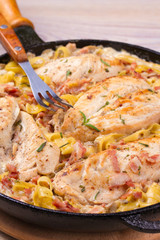 One pan chicken, bacon and mushrooms with egg noodles in frying pan. vertical