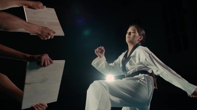 Asian beautiful girl fighter practicing to break the board with a kick of the feet, slow motion
