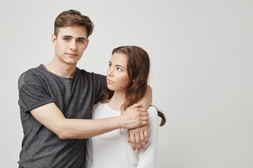 Portrait of couple hugging near the wall. Girlfriend thinks that he continues talk with his ex so...