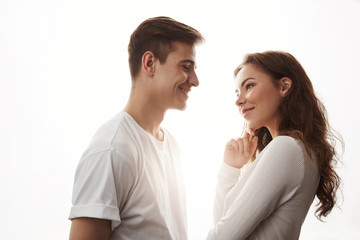 Obraz premium Sideways portrait of two adults in love. Guy flirts with beautiful girl trying to ask her for a date. He makes her smile. Every woman loves handsome boys with sense of humour