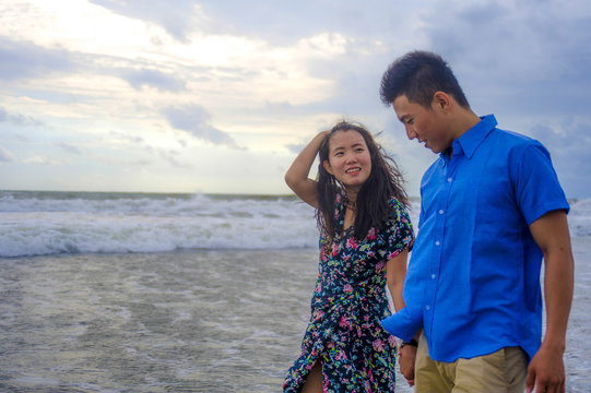 young beautiful Asian Chinese couple walking together on the beach happy in love enjoying holidays and relax smiling joyful in romance concept
