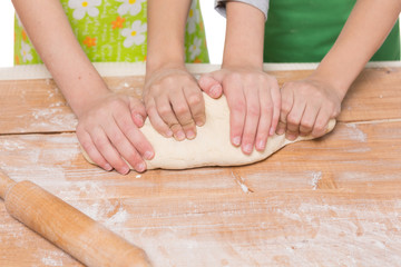 hands of children, boy and girl knead the dough on a wooden board