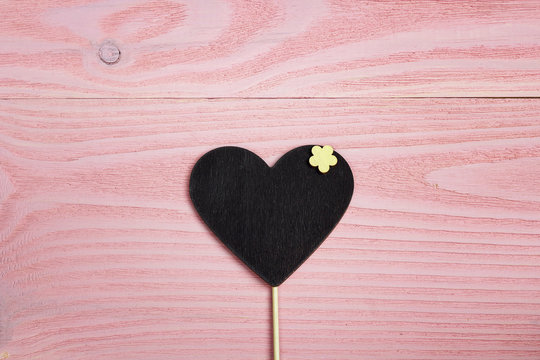 Blank heart-blackboard on pink wooden background. Space for text.