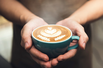 Fototapeta na wymiar Hands giving a cup of latte art coffee