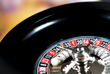 High contrast image of casino roulette and poker chips on bokeh background.