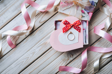 Marriage proposal concept. A wedding ring on a gift box on a wooden background. Top view. Copy space.