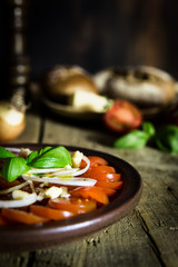 Tomatensalat mit Zwiebeln und Basilikum auf altem Holztisch