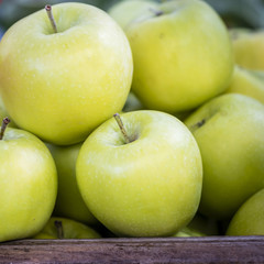 Fresh green apples in wooden box, closeup. Organic apple pile display at farmers market in Sydney, Australia.
