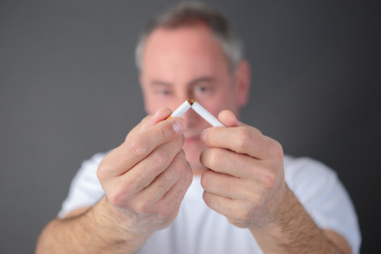 sadult man breaking cigarette