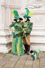 Obraz premium Venetian masks of Lovely Couple with dog on Venice Carnival in colorful and elegant costume San Zaccaria Square - Venice Carnival