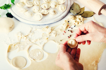 Obraz na płótnie Canvas Traditional russian pelmeni, ravioli, dumplings with meat on white concrete background. Parsley, quail eggs, pepper, rosemary, bay leaf and spices. Top view. Copy space