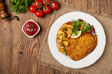 Chicken schnitzel, served with roasted potatoes and salad.