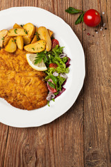 Chicken schnitzel, served with roasted potatoes and salad.