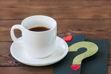 A cup of black coffee and a card on a wooden backdrop.