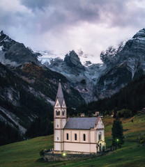 Fototapeta na wymiar Church with bell tower in Trafoi village against Stelvio mountains in dusk, Alps in Italy
