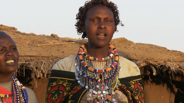 close up of a maasai woman in green singing at enkereri village near masai mara in kenya