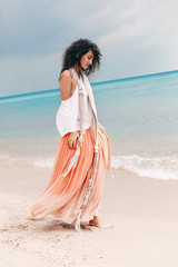 beautiful young stylish woman in pink skirt on the beach