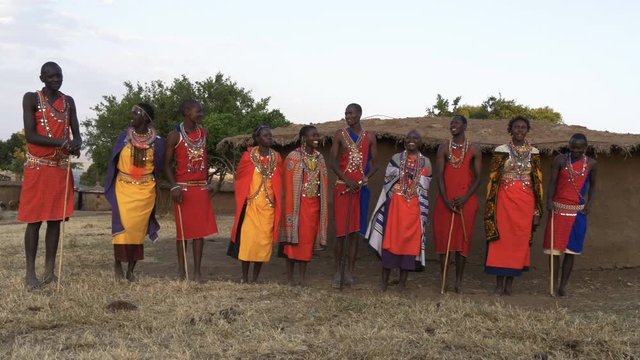 wide view of a group of ten maasai women and men singing from enkereri village near maasai mara game reserve in kenya