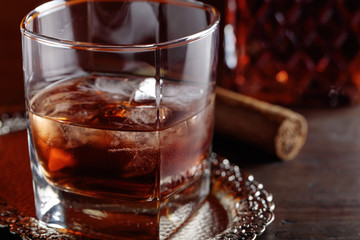 Glass of  whiskey and cigar on old wooden table.