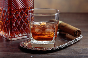 Glass of  whiskey and cigar on old wooden table.
