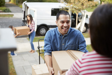 Children Helping Unload Boxes From Van On Family Moving In Day