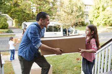 Children Helping Unload Boxes From Van On Family Moving In Day