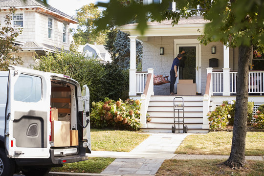 Courier Using Trolley To Deliver Package To House