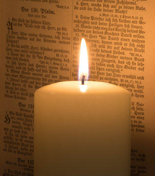 Kerze vor Bibel mit alter Schrift