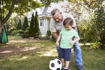 Grandfather Playing Soccer In Garden With Grandson