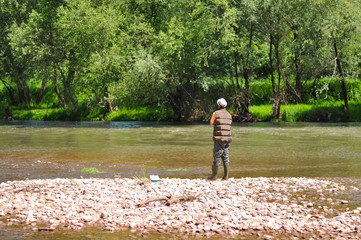 Man casts a hook on the river. Man fishing on wild river