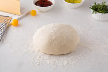 Raw dough for pizza with ingredients.